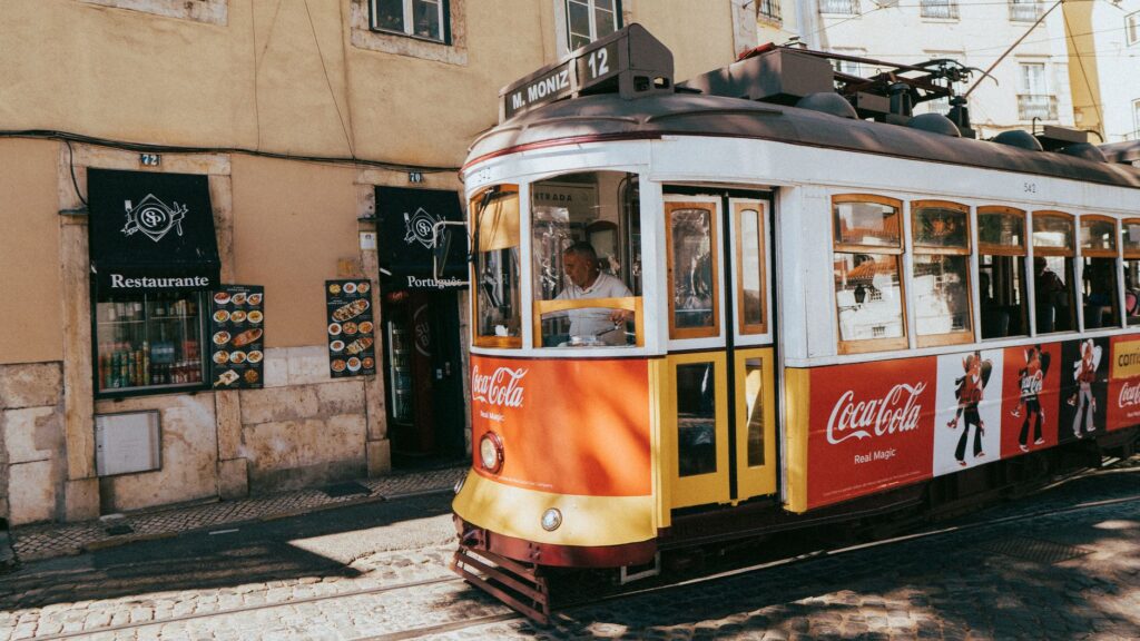 slow travel in Lisbon with sunlit tram tracks, tiled facades, and a quiet café table